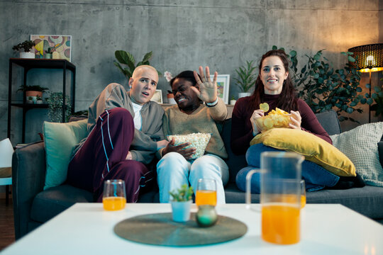 Diverse friends watching scary movie on sofa at home
