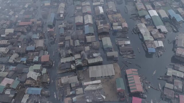 Aerial view of sprawling water village with stilted homes and boats navigating narrow waterways.