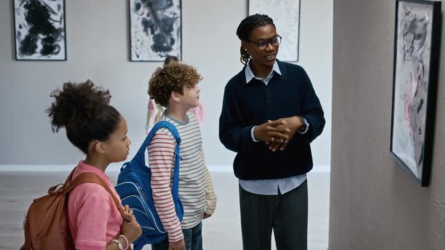 African American male teacher explaining modern painting to diverse children during school field trip in art gallery. Clip is ideal for educational marketing and museum promotion campaigns