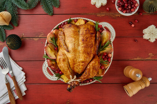 Overhead view of roast whole chicken with baked apples, cranberries