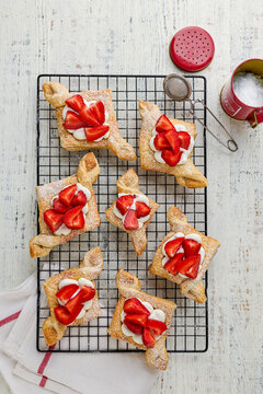 Overhead view of puff pastry strawberry danishes topped with cre