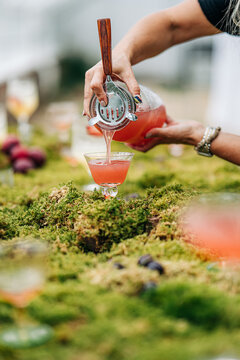 Woman pouring a craft cocktail on a mossy table