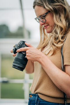 Female photographer with glasses checking her camera