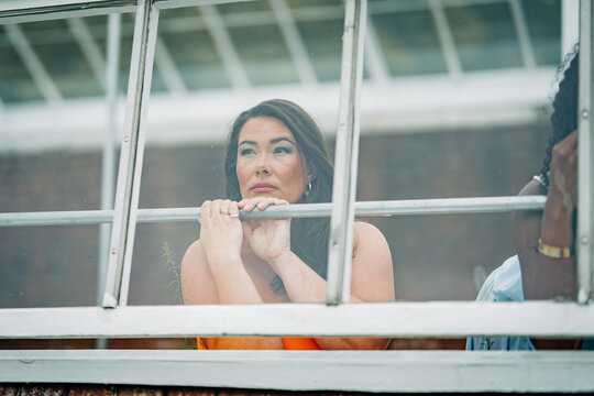 Thoughtful woman looking out of a greenhouse window