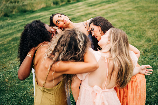 Diverse group of women in a supportive circle hug outdoors