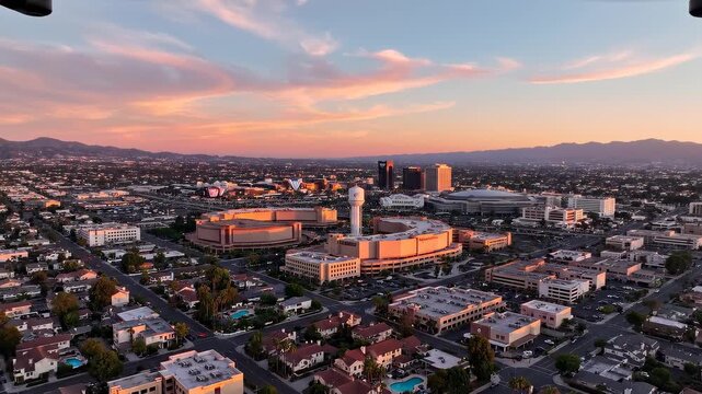 Aerial drone flies over urban sprawl during golden hour sunset with dramatic clouds
