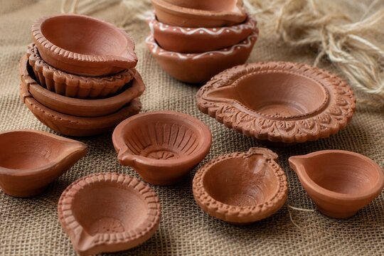 Handcrafted terracotta diya lamps arranged on rustic burlap for traditional Diwali celebration