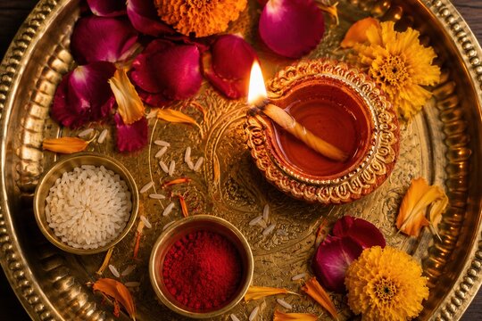 Glowing Diwali diya with marigolds and festive offerings on an ornate brass tray