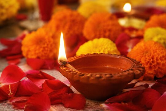 Traditional clay diya surrounded by marigolds and rose petals during Diwali celebration