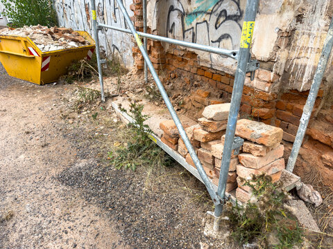 Renovation of an Old Red Brick House with Scaffolding and Construction Debris Skip
