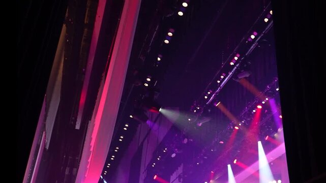 Cinematic horizontal shot of dynamic stage lighting with bright pink and white volumetric beams in a dark concert venue