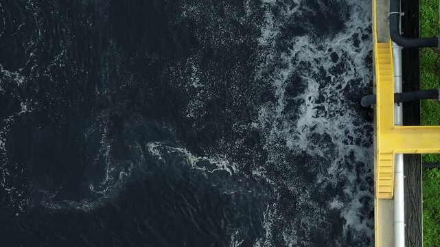 Aerial close up of dark wastewater in a factory treatment tank with foamy oxygenation, illustrating industrial water recovery, clean technology, and sustainable resource conservation. 4k.
