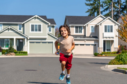 Happy boy running in suburban neighborhood street