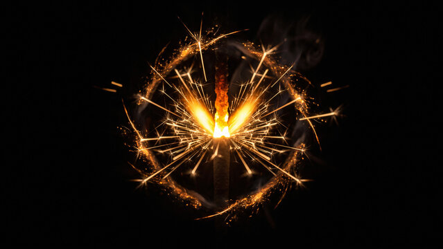 Close up of a burning fire fuse creating a fiery golden circle spark explosion against black background