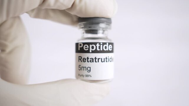 Gloved hand holding retatrutide peptide vial for medical research