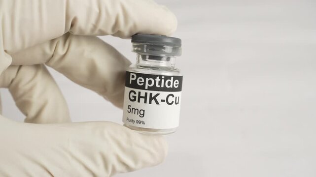 Gloved hand holding ghk-cu copper peptide vial