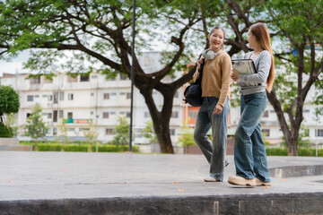 Obraz premium Two Young Asian Female College Students Walking and Talking Together on University Campus