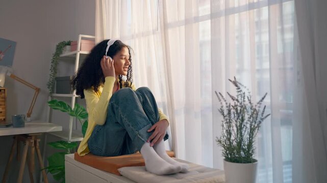 African American teenage girl wearing headphones and nodding head to the beat. 
