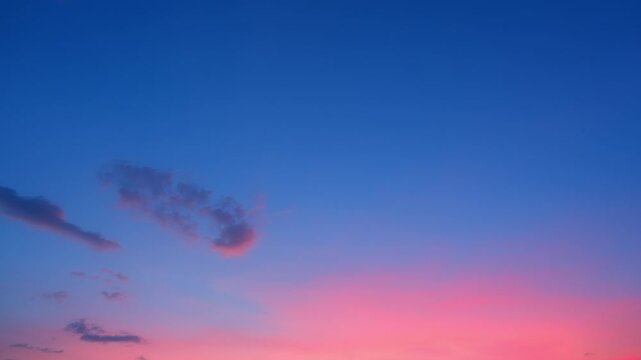 A sunset sky timelapse video showing a vivid blue and pink twilight gradient, with scattered cumulus clouds drifting across the open sky and creating a peaceful colorful evening atmosphere. 4k.
