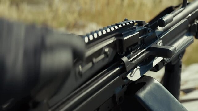 Extreme close-up of soldier's hand in tactical glove loading ammunition belt into machine gun and reloading weapon in combat environment. Military warfare detail concept for defense, armed forces and 