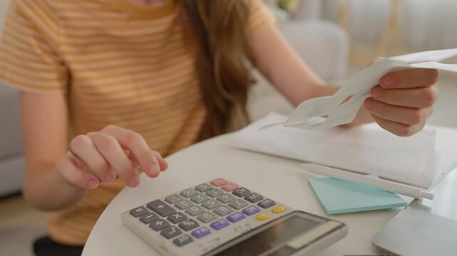 Close up of young woman sit on floor and calculating household expenses. 