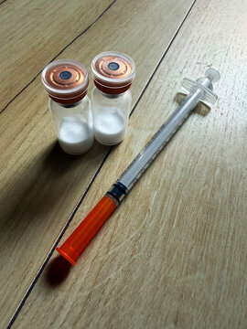 Reta, retatrutide peptide in a vial and bacteriostatic water on a wooden background.	
