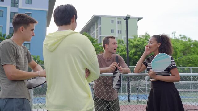 Group of diverse pickleball players standing together on outdoor court. 