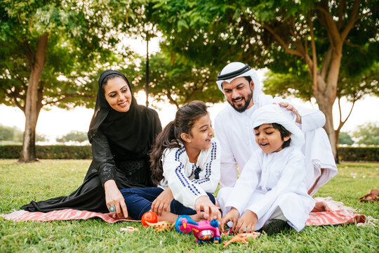 Happy Emirati family spending time together outdoor in Dubai in a public park making a picnic.