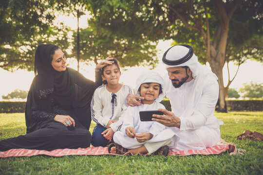 Happy Emirati family spending time together outdoor in Dubai in a public park making a picnic.