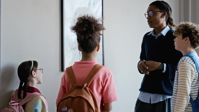 African American male teacher explaining abstract painting to diverse school children in art gallery. Footage ideal for educational programs, museum promotions, and school field trip advertisements