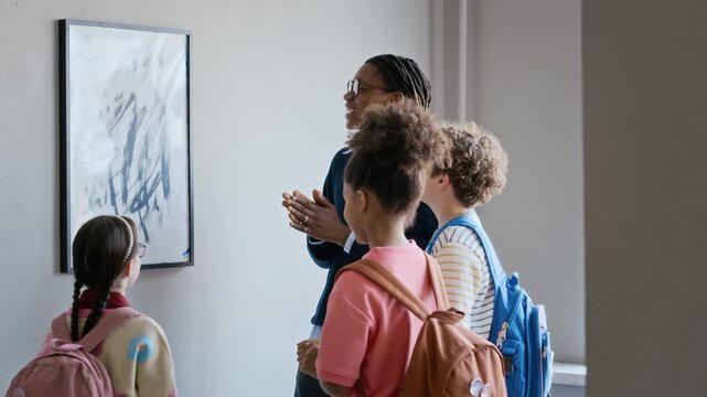 Black male educator explaining abstract painting to diverse school children in art gallery clip is suitable for museum marketing and school field trip promotional videos