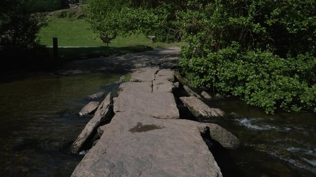 A steady shot capturing Tarr Steps in Exmoor National Park, showcasing the ancient clapper bridge stretching across the gently flowing River Barle.