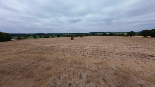 FPV drone fast low flight skim over rural farmland near high voltage power lines and pylons UK