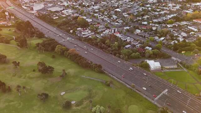Northwestern Motorway traffic and Chamberlain Park golf course at sunset in Auckland, New Zealand. Aerial droen view