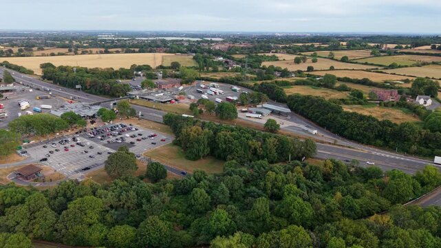 Aerial orbit view of busy motorway service station and traffic slip roads on M6 in Warwickshire UK