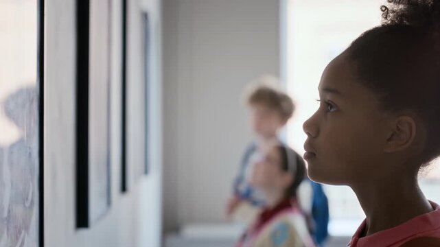 Black girl looking at paintings in art gallery during school field trip with classmates in background. Perfect for educational programs, museum promotions, and youth learning concepts