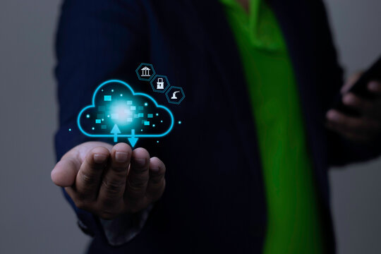 Cloud technology for banking, security, and industrial data management concept with businessman holding glowing cloud icon with bank, lock, and robotic arm symbols.
