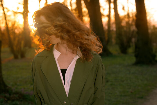 Curly haired woman in motion blur with dramatic sunset glare in a park