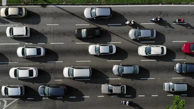 Aerial slow motion footage of vehicles moving along a busy multilane urban road.