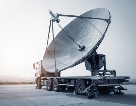 A large parabolic antenna on a heavy truck chassis, featuring a weathered matte finish and textured mesh for communications infrastructure and defense technology, with copy space.