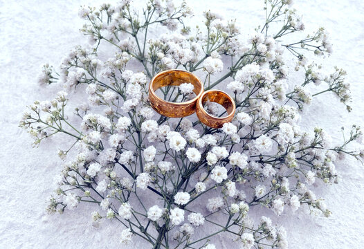 Beautiful golden wedding rings placed delicately on snowy white gypsophila flowers arrangement