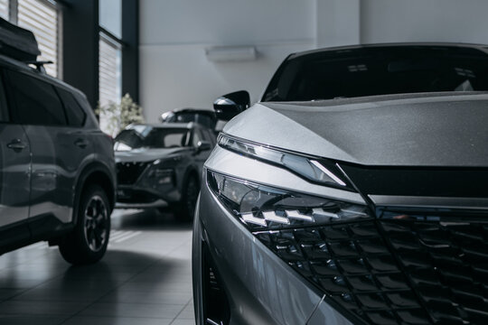 Front section of a modern car in close-up inside a bright automotive showroom. Concept new vehicle, dealership and automotive sales.