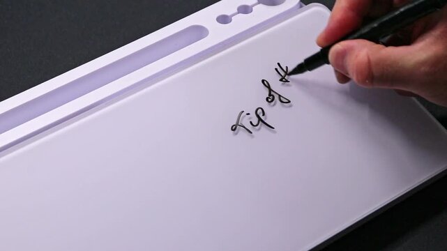 European male hand writing tip of the century on whiteboard with black pen and erases it with white sponge afterwards for seamless looping message writing on whiteboard. Hint or inportant tips.