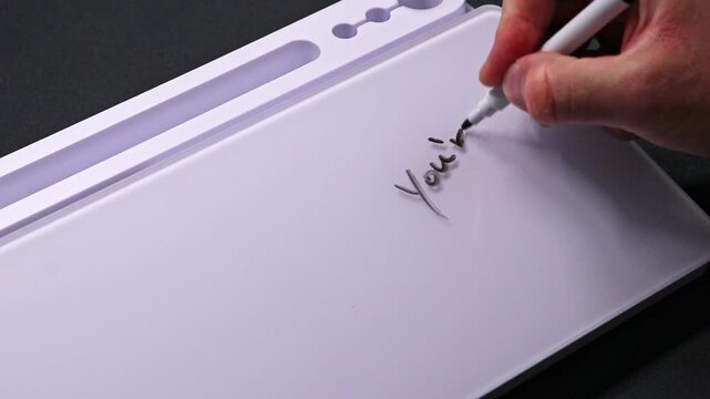 European male hand writing you&acute;re awesome on whiteboard with black pen and erases it with white sponge afterwards for seamless looping message writing on whiteboard. Motivational quote positive text.