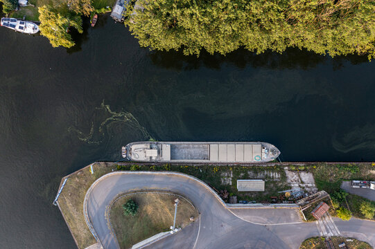 Aerial view of a cargo barge moored along the riverbank near the Container Terminal METRANS in Wildau, Brandenburg, Germany.