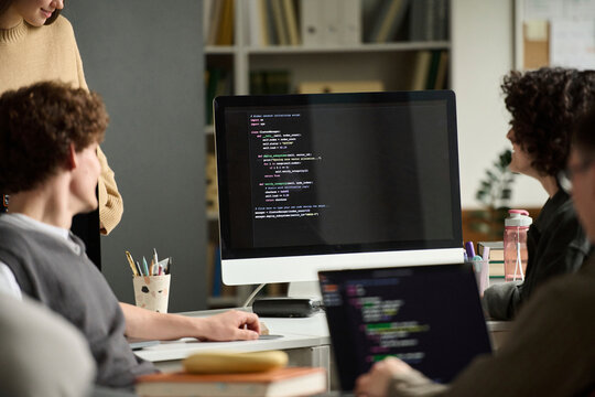 Group of students looking at computer screen while coding in class