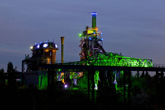 Germany, Nordrhein-Westfalen, Duisburg, Duisburg-Nord Landscape Park, View of illuminated blast furnace and smoke stacks of old industrial plant