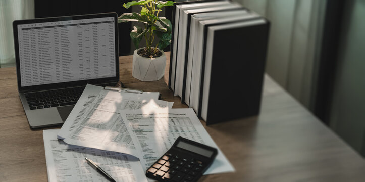 Financial reports with laptop and calculator on office desk for audit, compliance, accounting review, document verification, internal control with copy space.