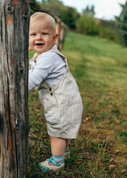 Smiling boy explores the rural countryside by a wooden fence
