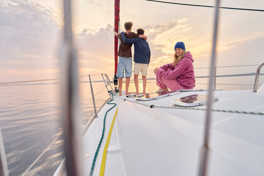 Mother and sons enjoy a sailing vacation on the ocean at sunset
